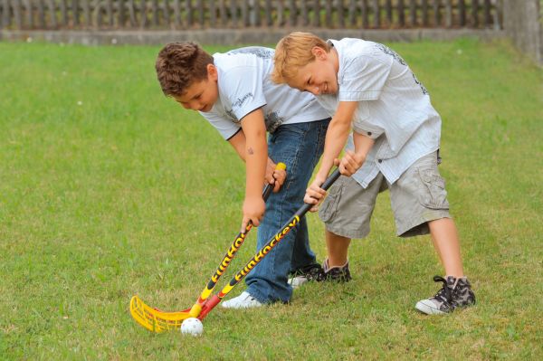 Zwei Kinder spielen Hockey auf dem Rasen mit den Schlägern von Winsport.