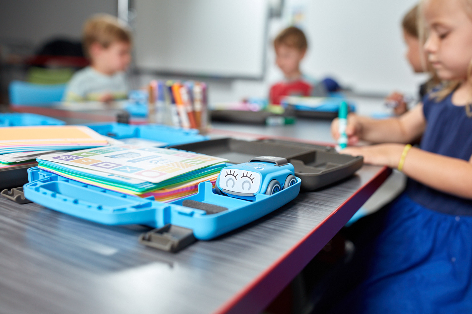 Kinder spielen mit den Sphero Robotics Lernrobotern, vor den Kindern liegen geöffnete Koffer mit Roboterteilen und Zubehör.