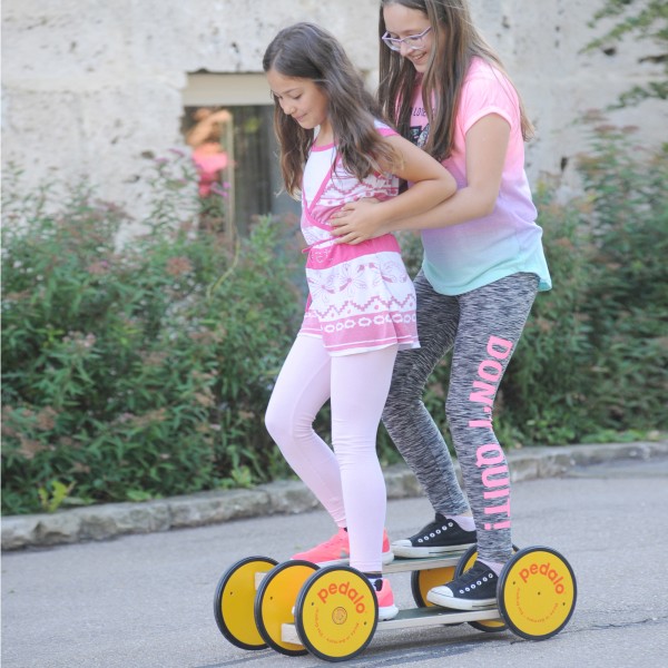 Zwei Mädchen fahren zusammen auf der Pedalo Combi für 2 Personen die Straße entlang