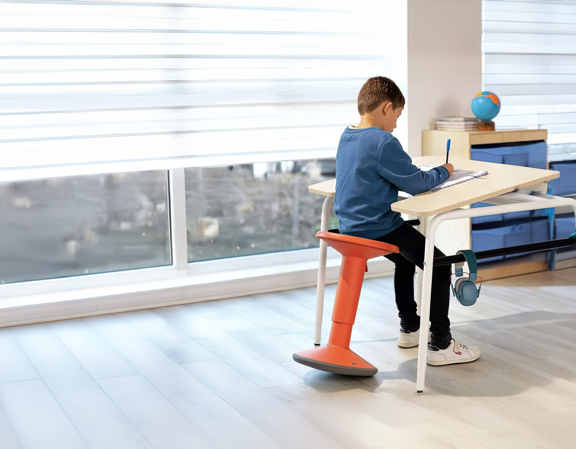 Junge sitzt auf ergonomischen Hocker von Wesco in Orange