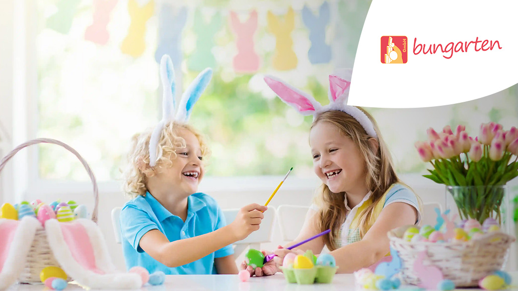 Zwei Kinder mit Hasenohren auf sitzen an einem Tisch. Der Raum ist mit Osterdeko geschmückt. In der Ecke ist ein Bungarten Logo.