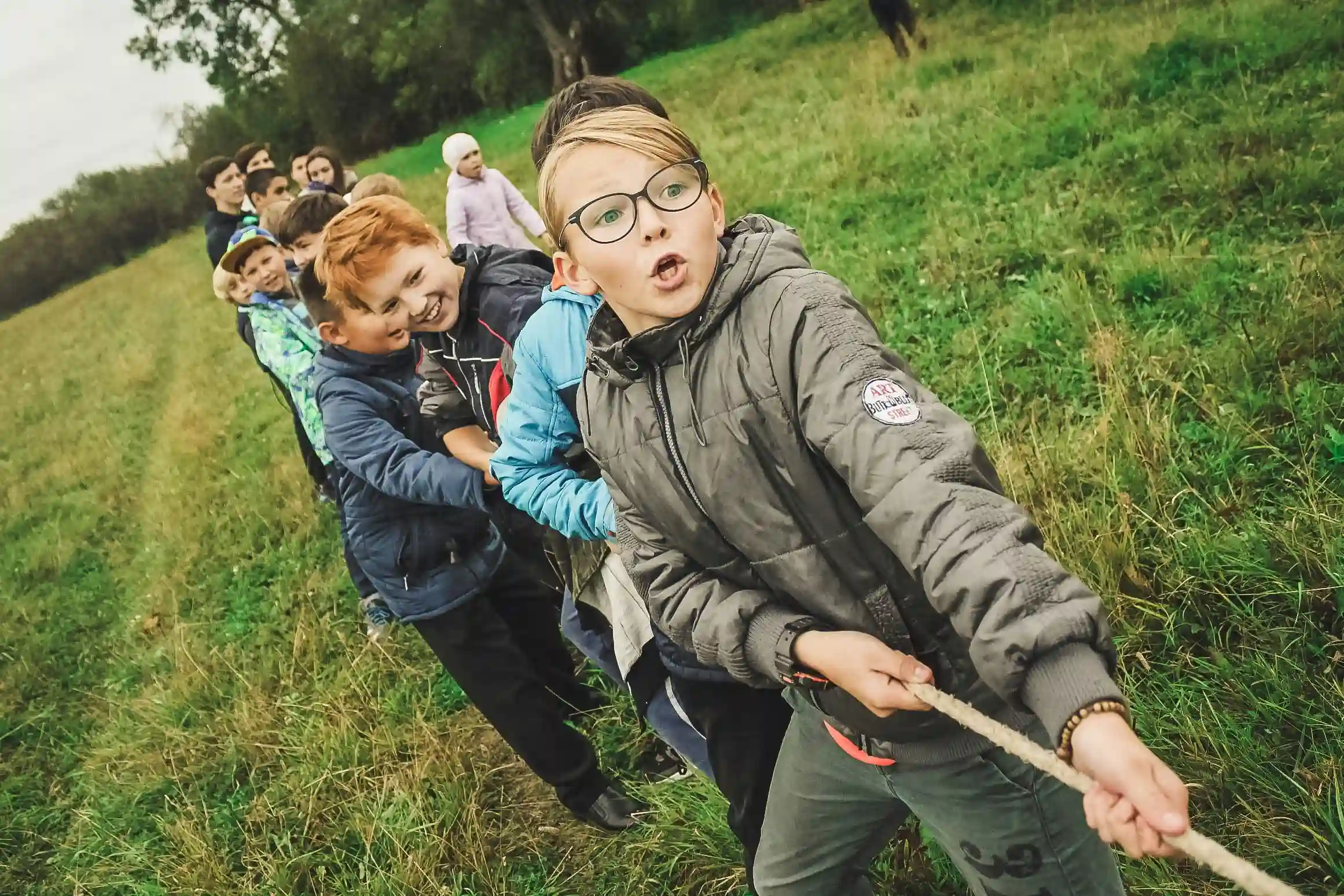 Zu sehen sind mehrere Kinder auf einer Wiese beim Tauziehen.