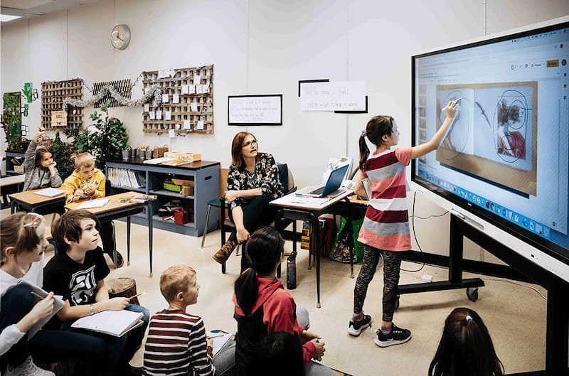 Ein Mädchen steht im Unterricht vorne am Smart display und zeichnet etwas auf das interaktive Unterrichtsboard.