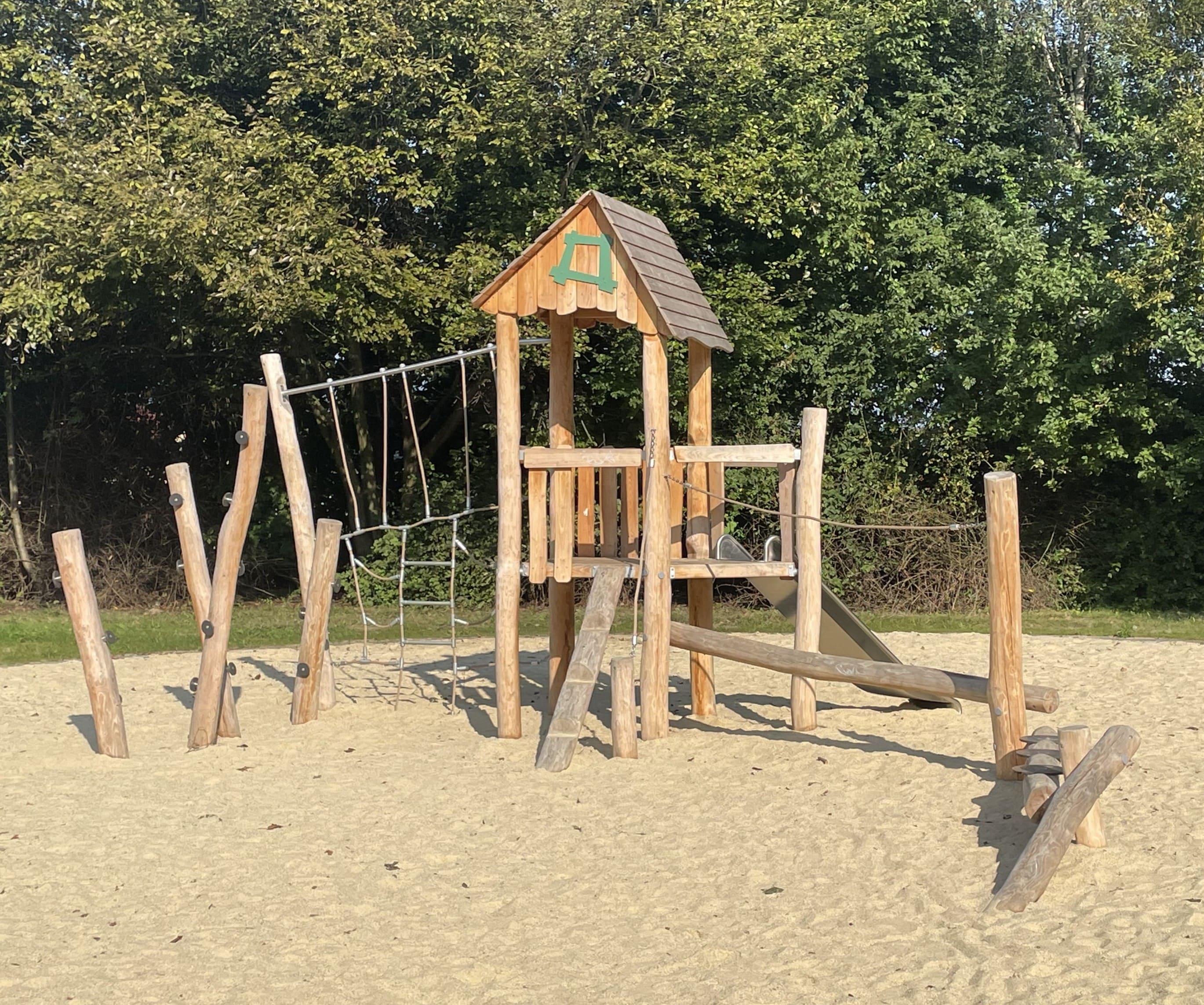 Ein großes Spielplatzgerät aus Holz, welches im Sand steht