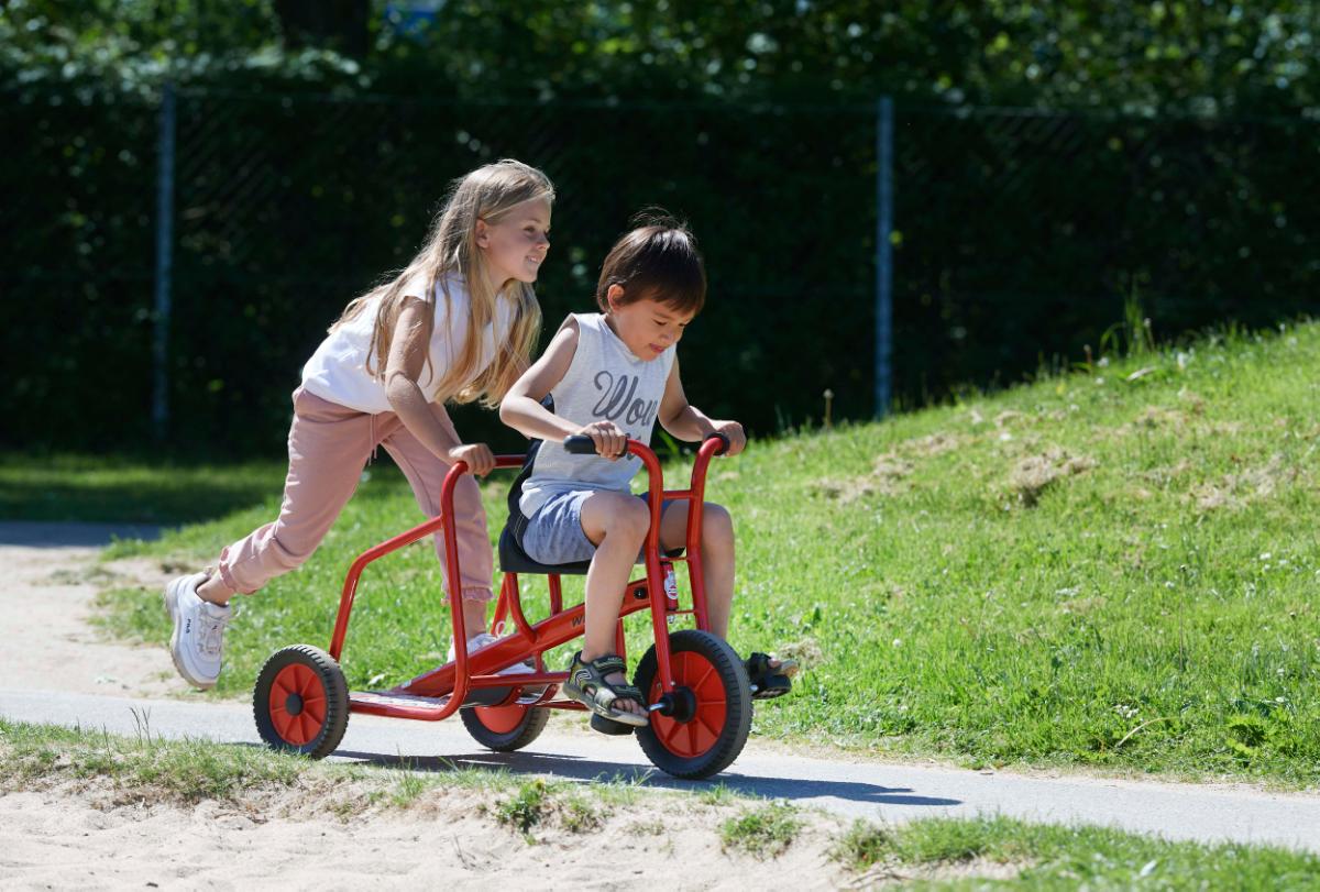 Zwei Kinder fahren auf einem Dreirad von Winther.