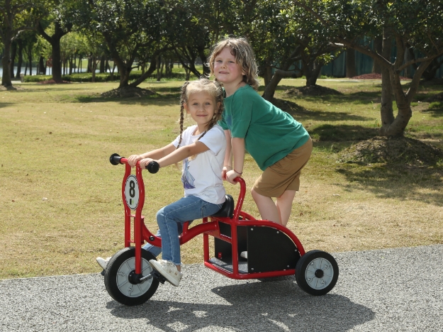 Zwei Kinder fahren mit einem Kindertaxi von Wisdom.